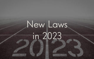 A picture of a foggy running track. The lanes quickly vanish into a thick bank of mist. In one lane, "20" is written in stenciled text. In the next, "23" is written in the same font. Overlaid on the image is the title of the blog post: "New Laws in 2023."